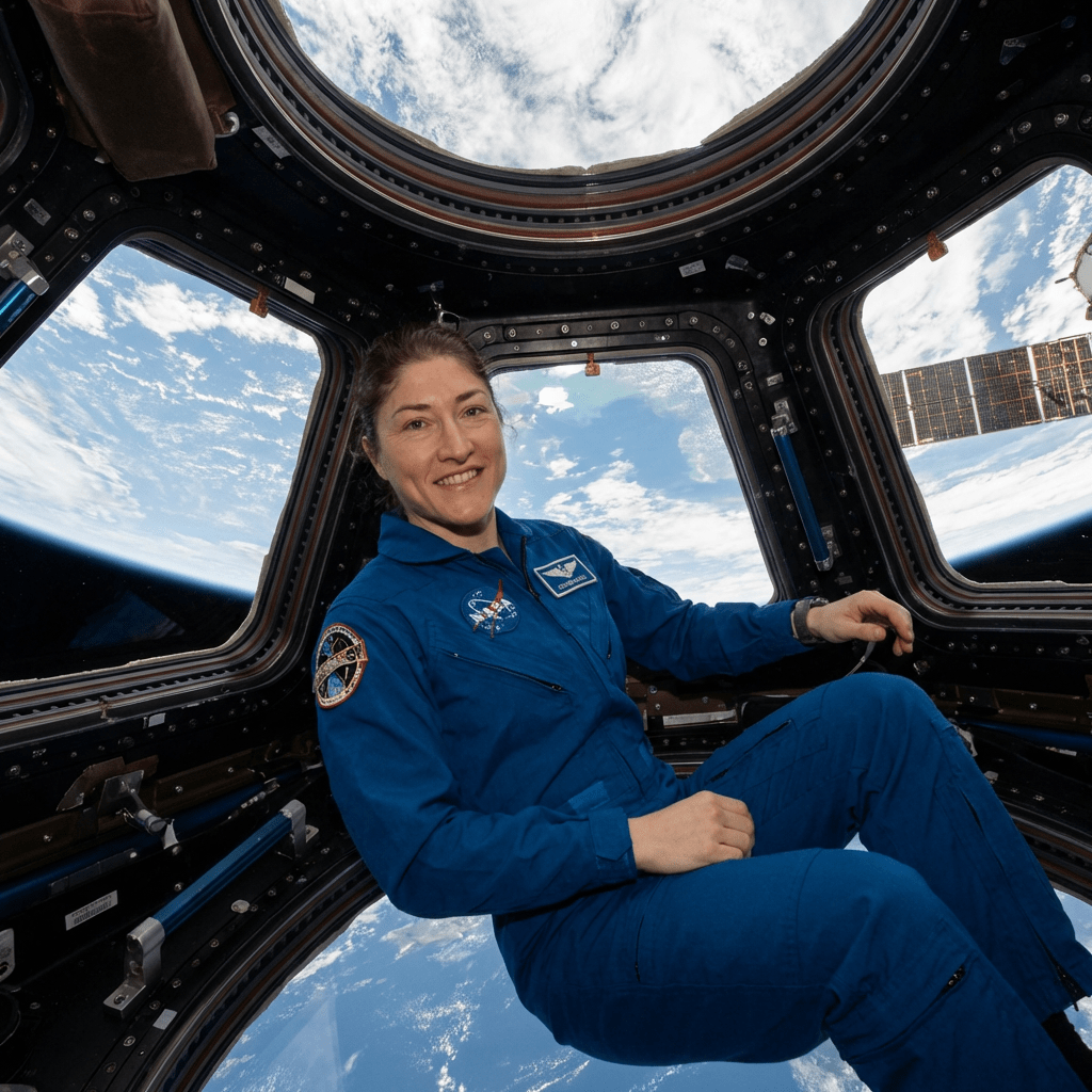 Astronaut Christina Koch sits inside the ISS Cupola with Earth visible through the windows.